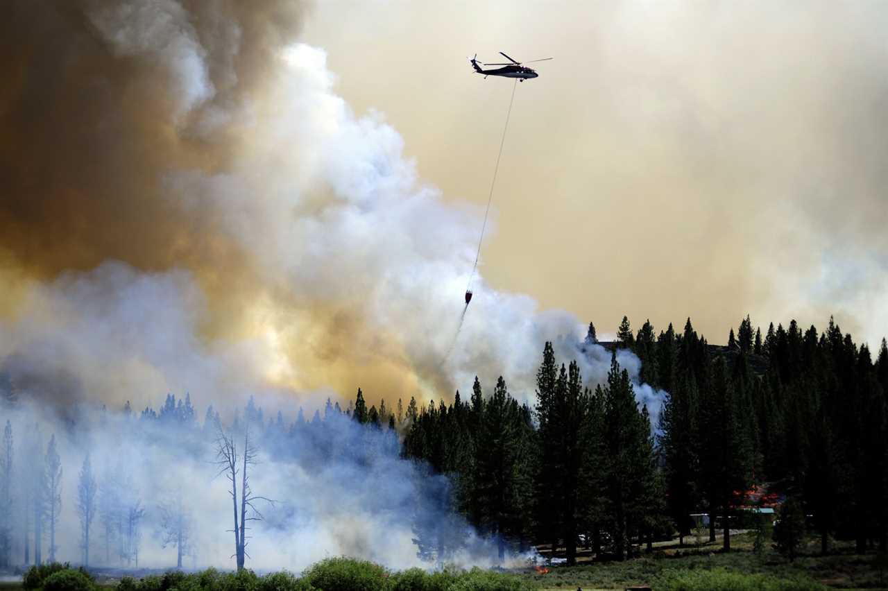 DOYLE, CALIFORNIA, USA - JULY 12: A helicopter tries to extinguish the northeastern flank of the Sugar Fire as it continues to show active fire behavior in Doyle, California, United States on July 12, 2021. Firefighters were able to bring the containment up to 26% by the late afternoon. The Fire is currently at 91,200 acres. (Photo by Neal Waters/Anadolu Agency via Getty Images)