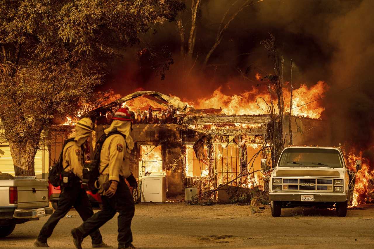 Firefighters pass a burning home as the Sugar Fire, part of the Beckwourth Complex Fire, tears through Doyle, Calif., on Saturday, July 10, 2021. Pushed by heavy winds, the fire came out of the hills and destroyed multiple residences in central Doyle. (AP Photo/Noah Berger)