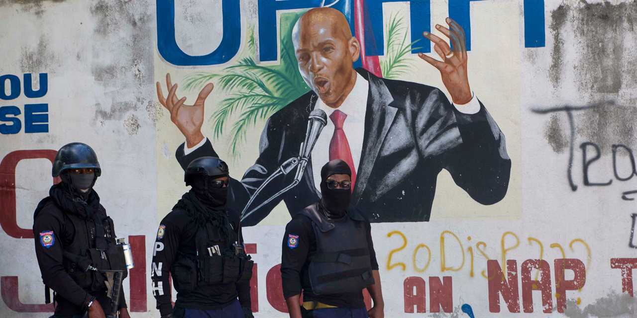 Armed police officers stand in front of a mural of Haitian President Jovenel Moïse