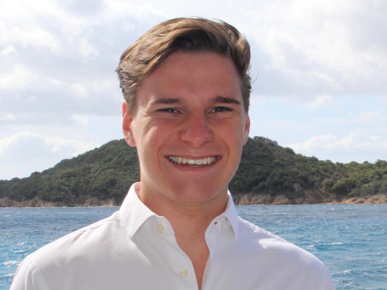 Oliver Daeman smiling in front of water and mountain