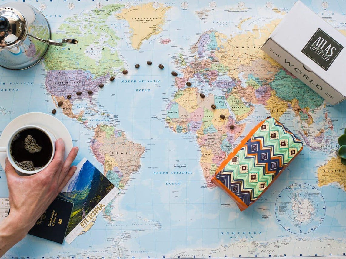 bags and cups of coffee from Atlas Coffee Club sit on a world map as part of the best coffee subscription in 2021