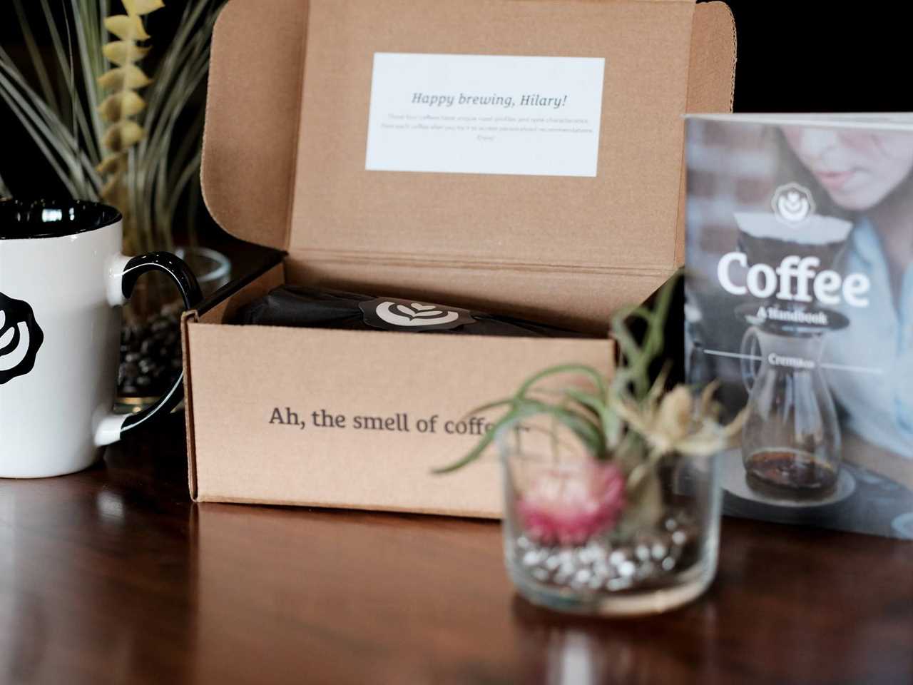 A box containing bags of coffee from crema.co sits open next to a plant as part of the best coffee subscription in 2021