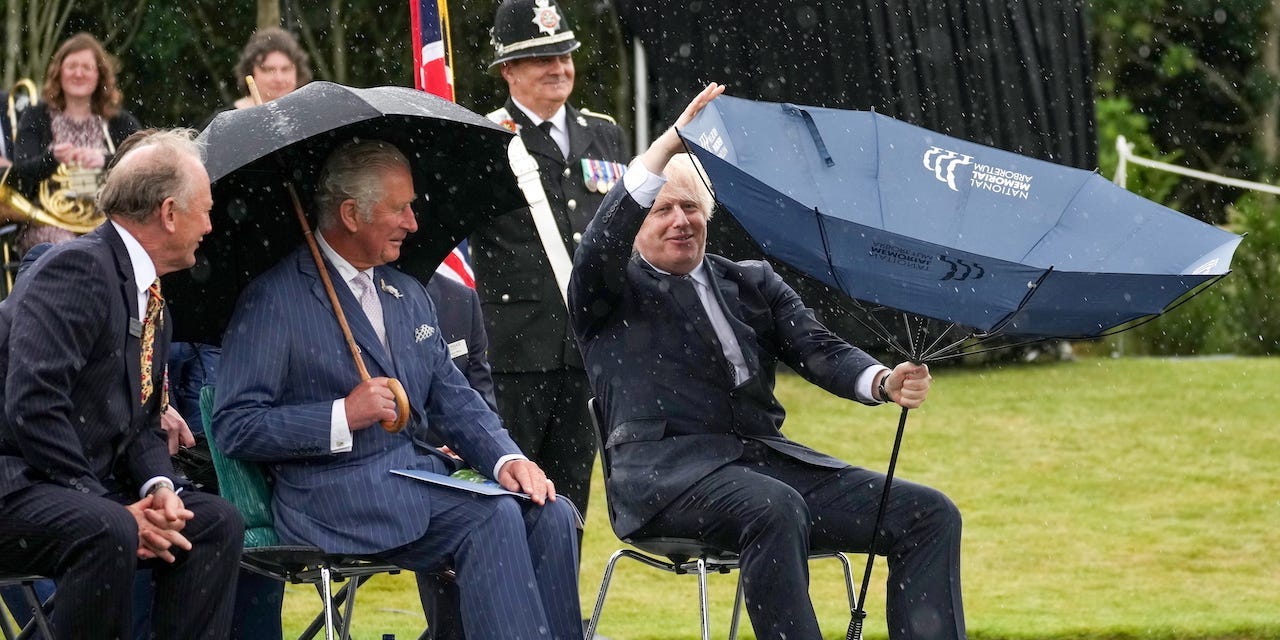 UK Prime Minister Boris Johnson's umbrella turns inside-out as he struggles to open it at the National Memorial Arboretum in Staffordshire, Britain July 28, 2021.