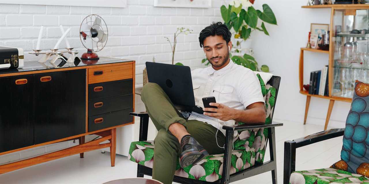 man using laptop and phone at home