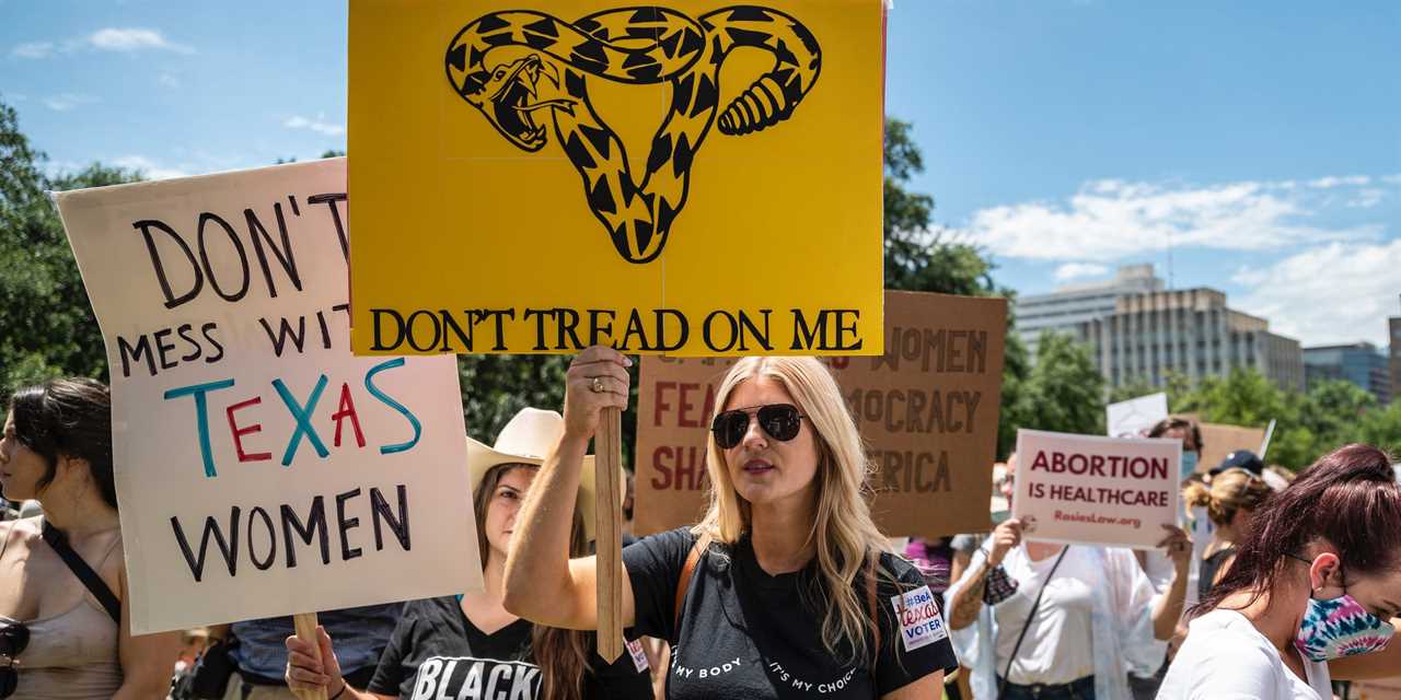 Protesters hold up signs at a protest against Texas' new abortion law outside the state capitol on May 29, 2021 in Austin, Texas.