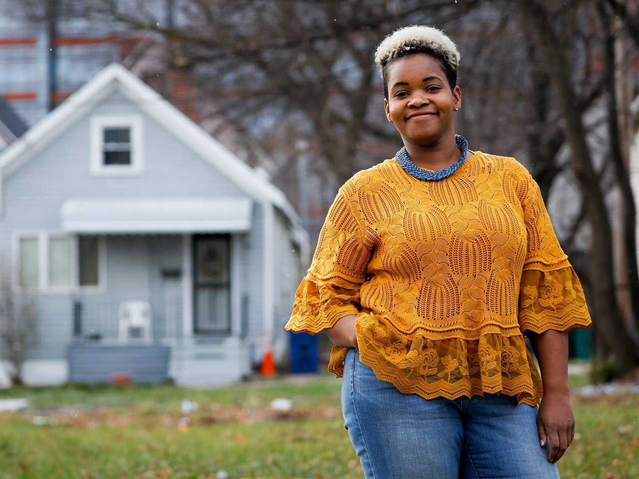 india walton stands outside in front of a house