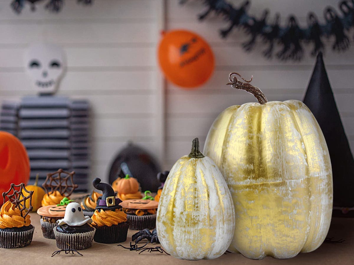 Image of a tabletop with orange cupcakes, two gold pumpkins, and other Halloween decorations from Amazon, best Halloween decorations 2021