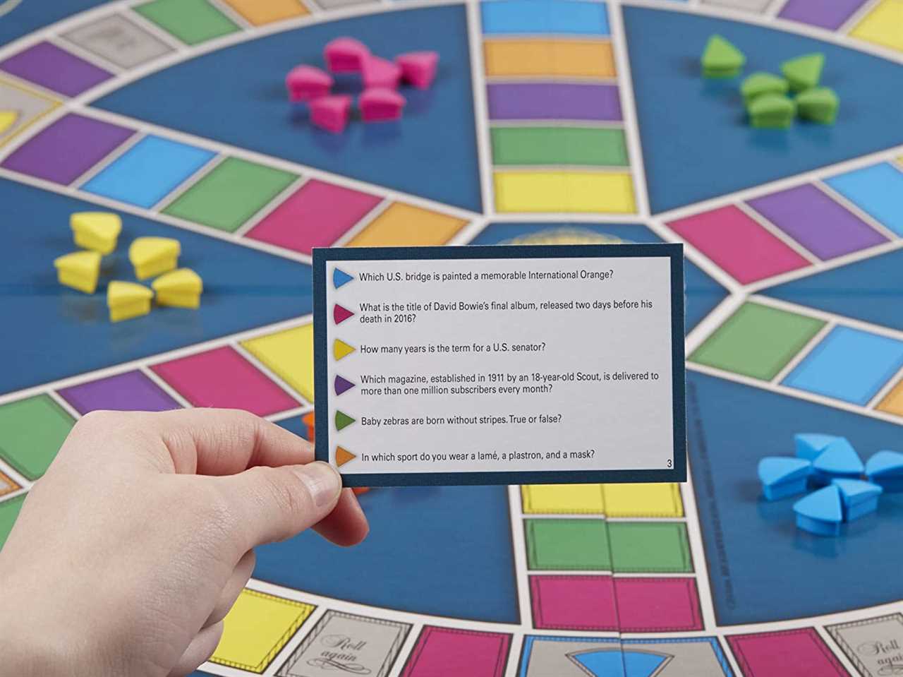 An image of the Tirival Pursuit game board with a question card and sets of green, pink, yellow, and blue game pieces