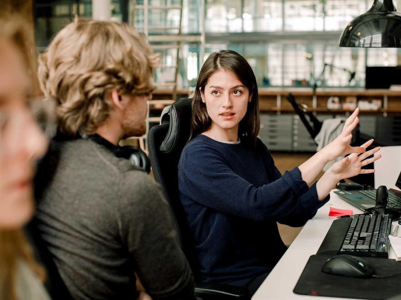 coworker explaining something on computer to other coworkers in office