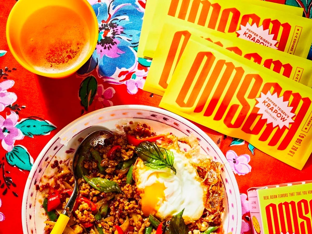 Yellow Omsom Asian meal starter packs next to bowl of Krapow, a chili basil stir fry, as part of the best Asian American food and drink brands in 2021