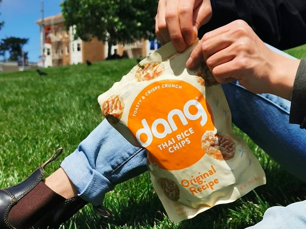 Hand ripping open a bag of Dang Foods Thai rice cakes snacks - Best Asian American food and drink brands in 2021