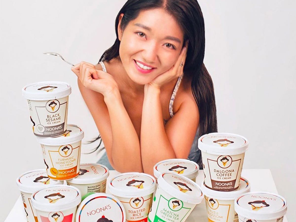 Woman smiling and posing in front of stacks of ice cream from Noona's Ice Cream - Best Asian American food and drink brands in 2021