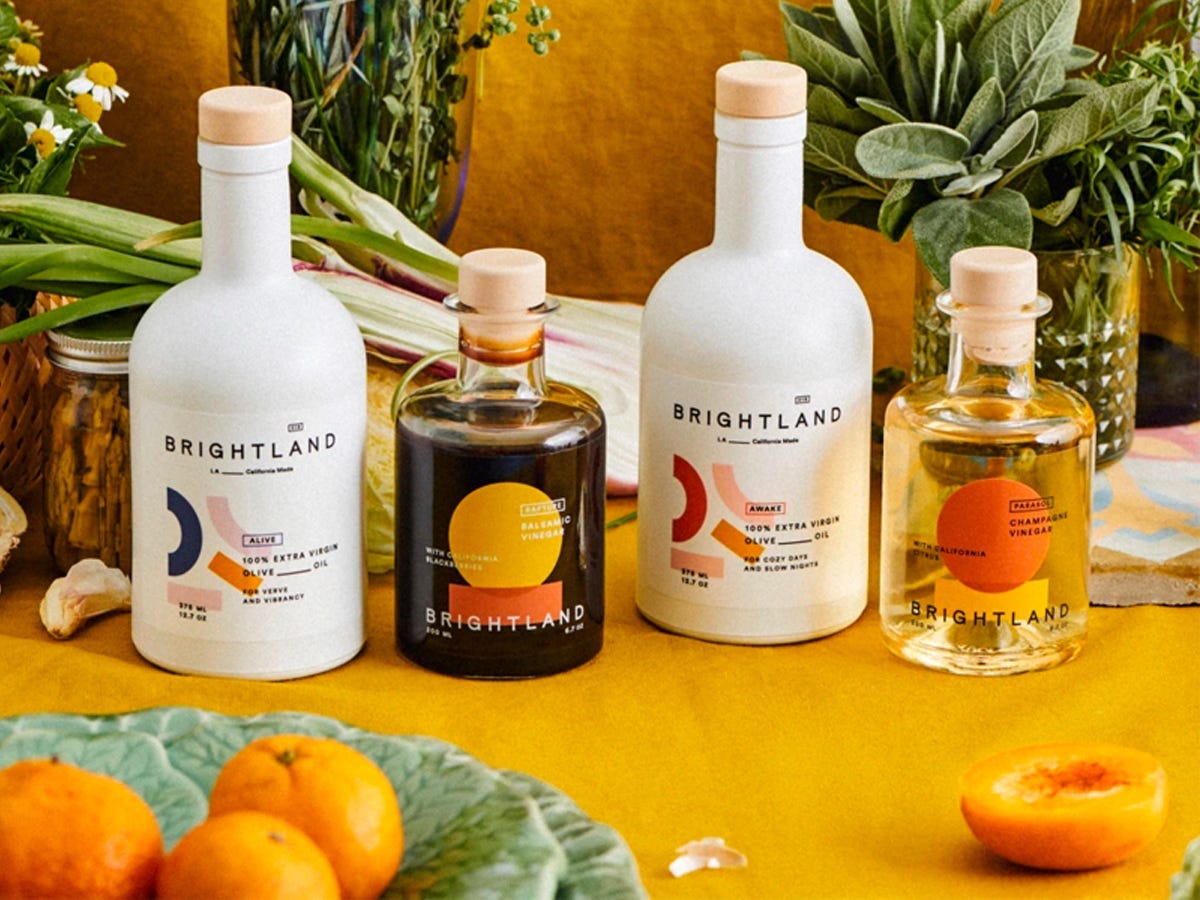Brightland olive oil and vinegars on a table with fruits and plants - Best Asian American food and drink brands in 2021