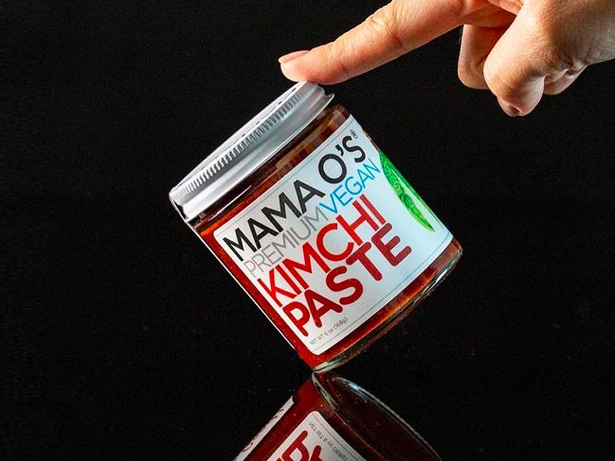 Finger pushing jar of vegan kimchi from Mama O’s - Best Asian American food and drink brands in 2021