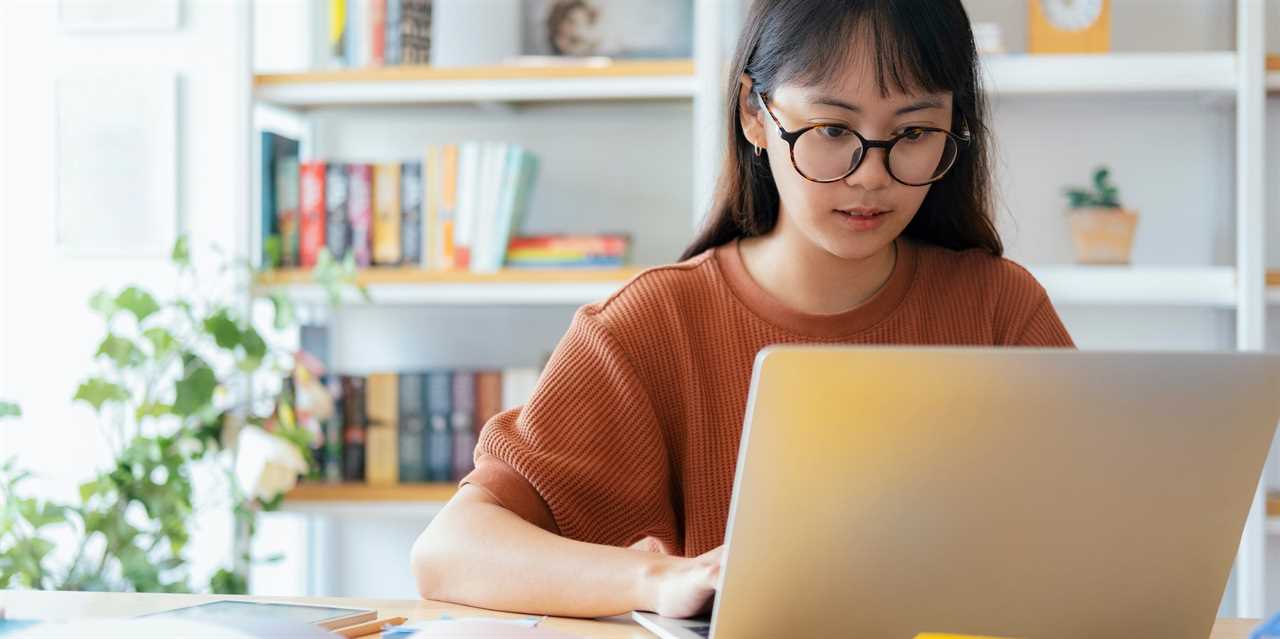 young student using laptop and textbooks at desk