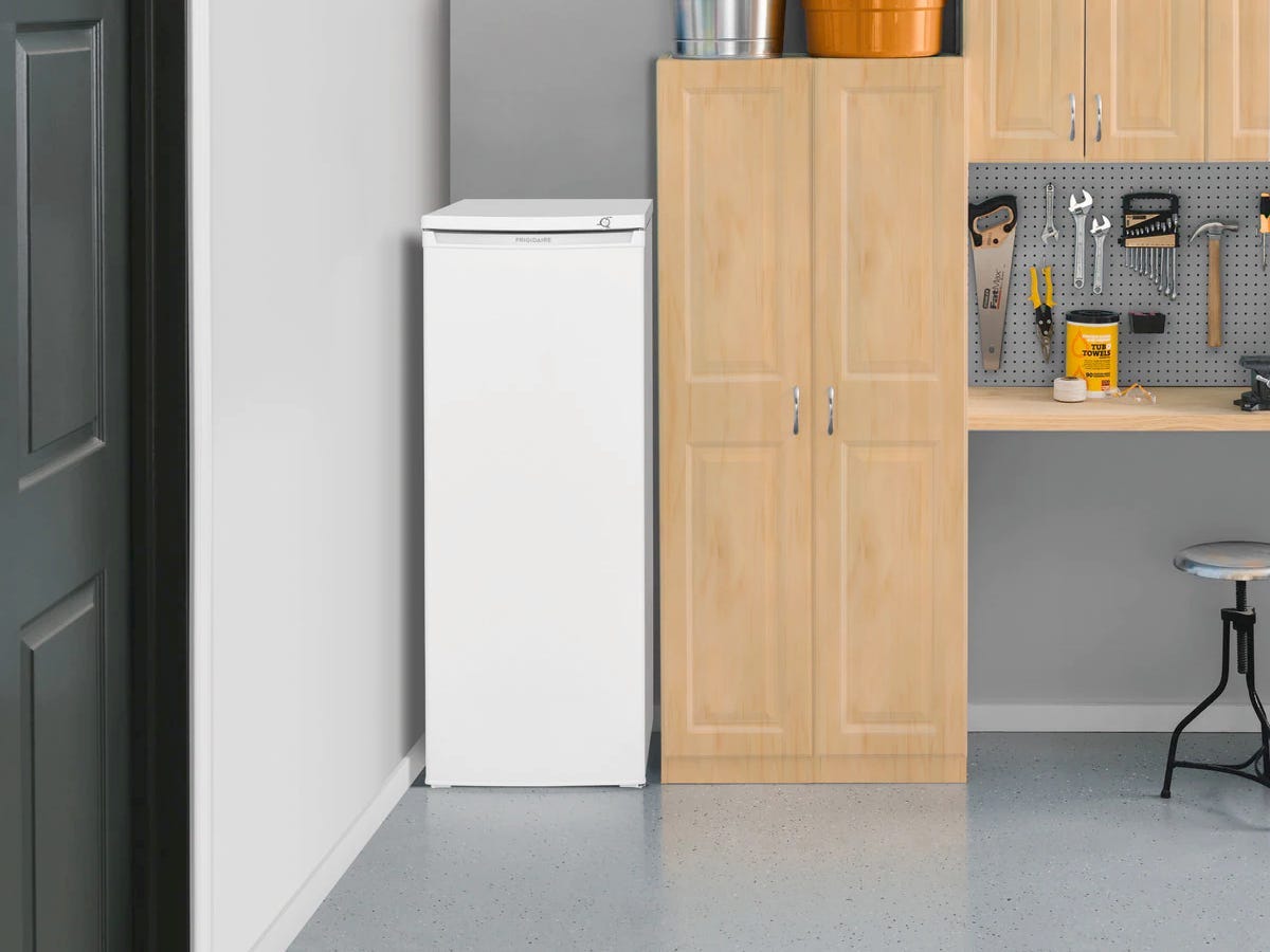 Image of the Frigidaire FFFU06M1TW freezer next to a shelving system in a garage for best freezers of 2021