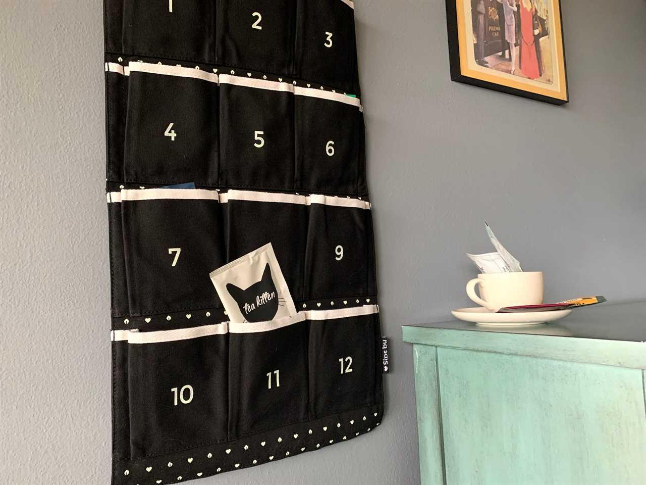 Image of Sips by tea advent calendar hanging on wall by table with cup for best advent calendars 2021