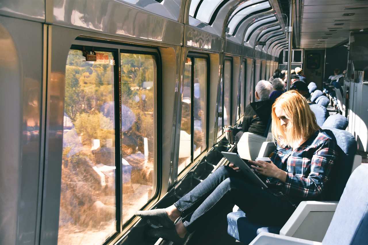 a woman reading a book in a seat on amtrak train in front of a window