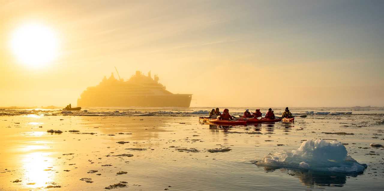 kayakers on icy water with the Le Commandant Charcot in the back