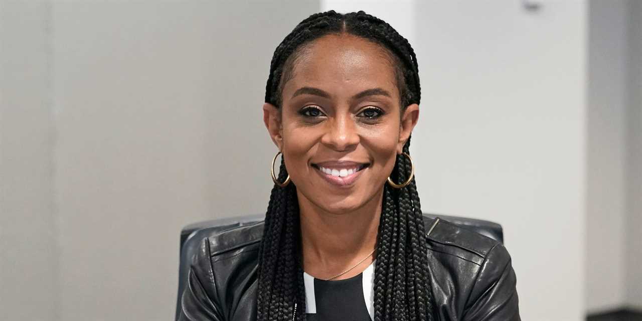 Democratic candidate Shontel Brown is shown wearing a black leather jacket, black shirt, and gold hoop earrings