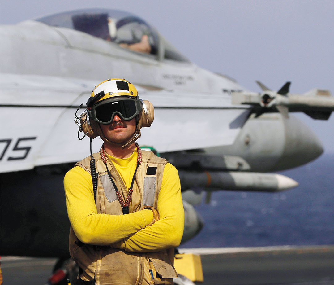 Military personnel in yellow shirt on fighter ship