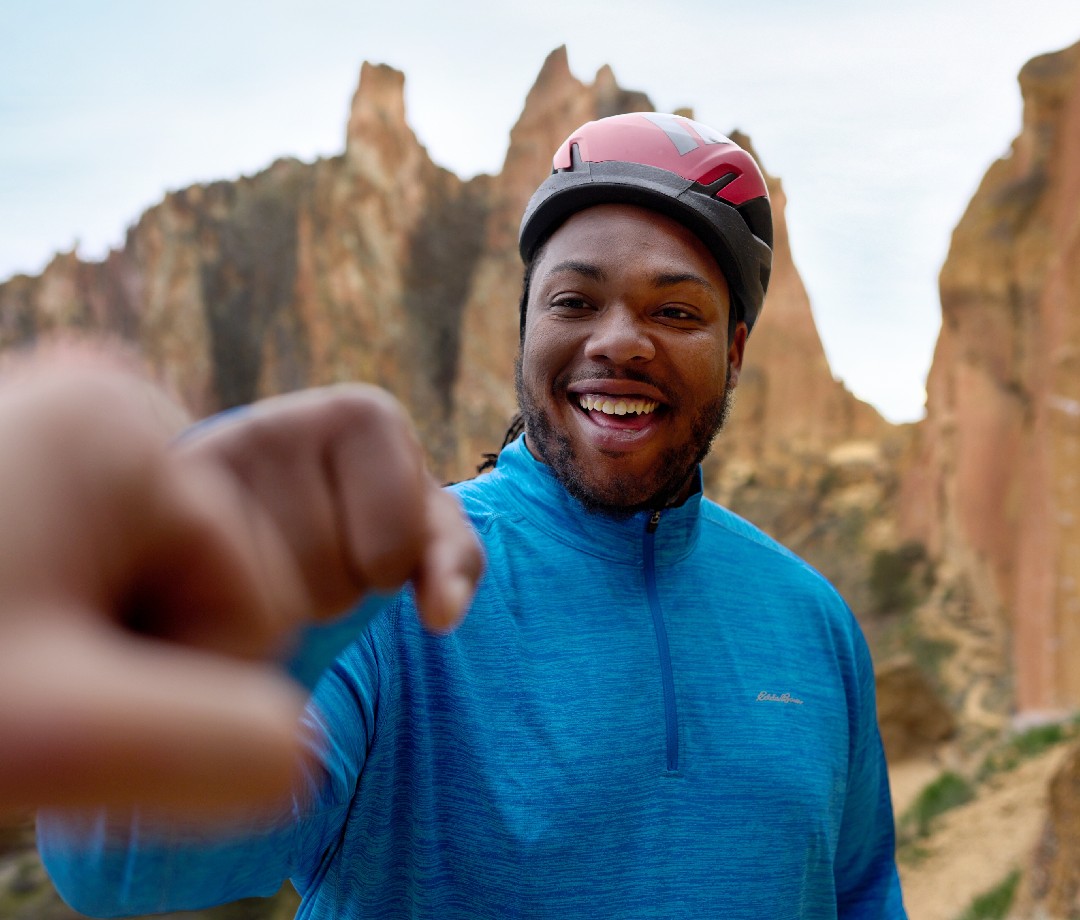 Happy hiker in a helmet fist bumps another hiker out of the frame