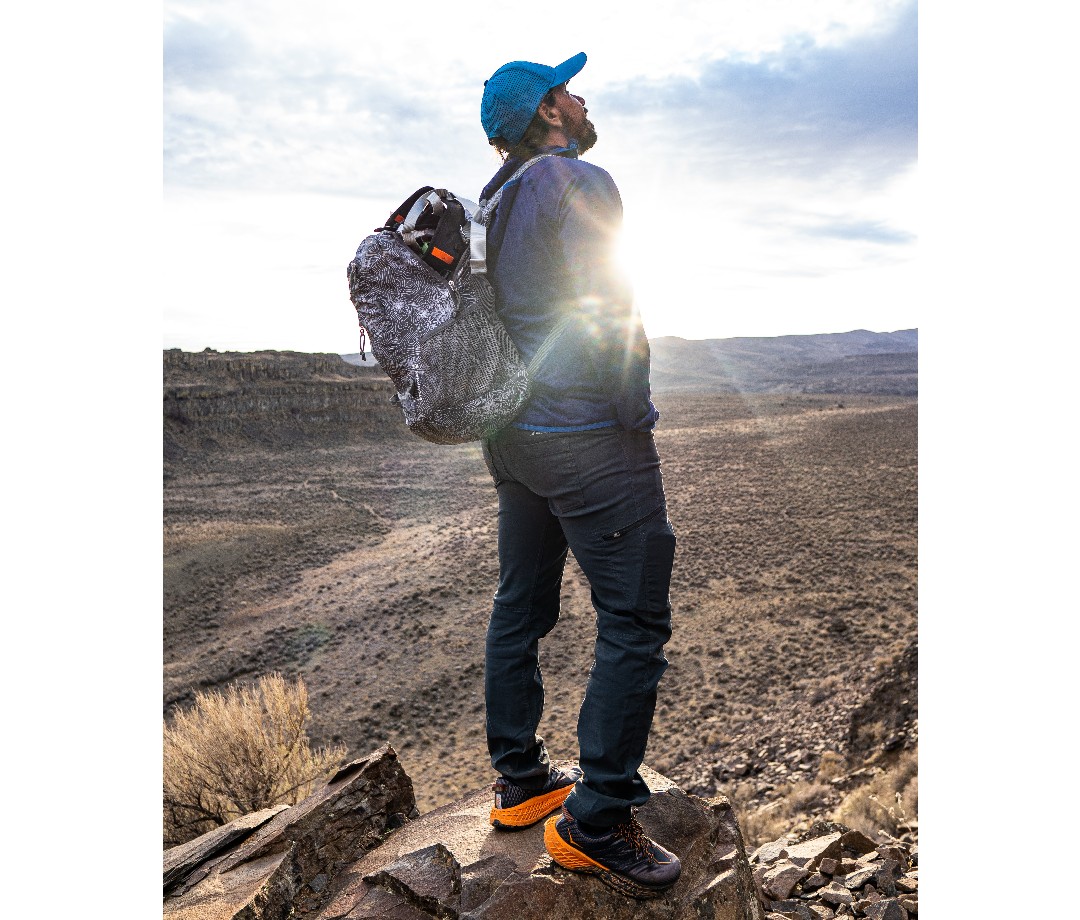 Hiker standing with his backpack on gazing up at the sky in the sunlight