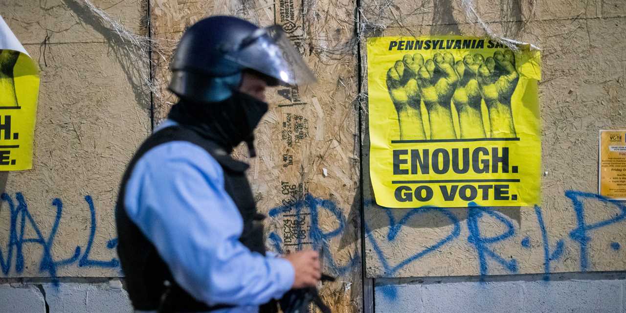 Police walking by boarded up building