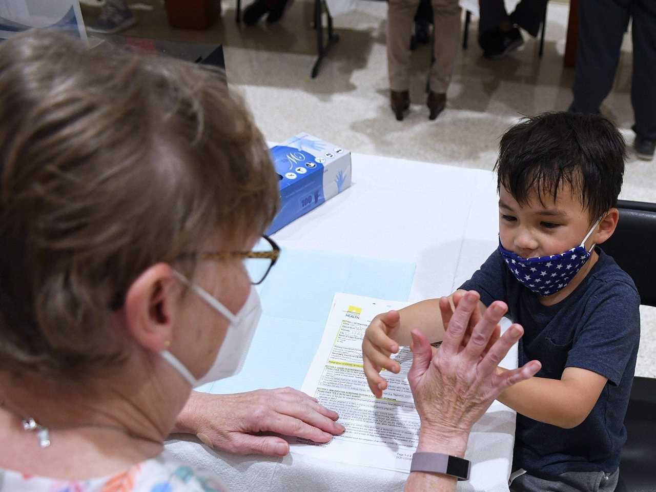 A boy gives a nurse a high five before receiving a shot of the Pfizer COVID-19 vaccine at a vaccination site for 5-11 year-olds at Eastmonte Park in Florida