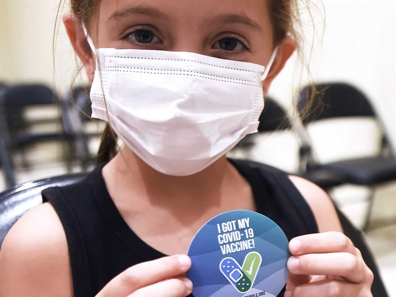 A little girl displays a vaccination sticker after receiving a shot of the Pfizer COVID-19 vaccine at a vaccination site for 5-11 year-olds at Eastmonte Park in Florida.