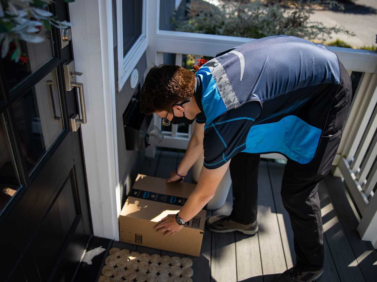 Amazon delivery driver placing a package on a front porch