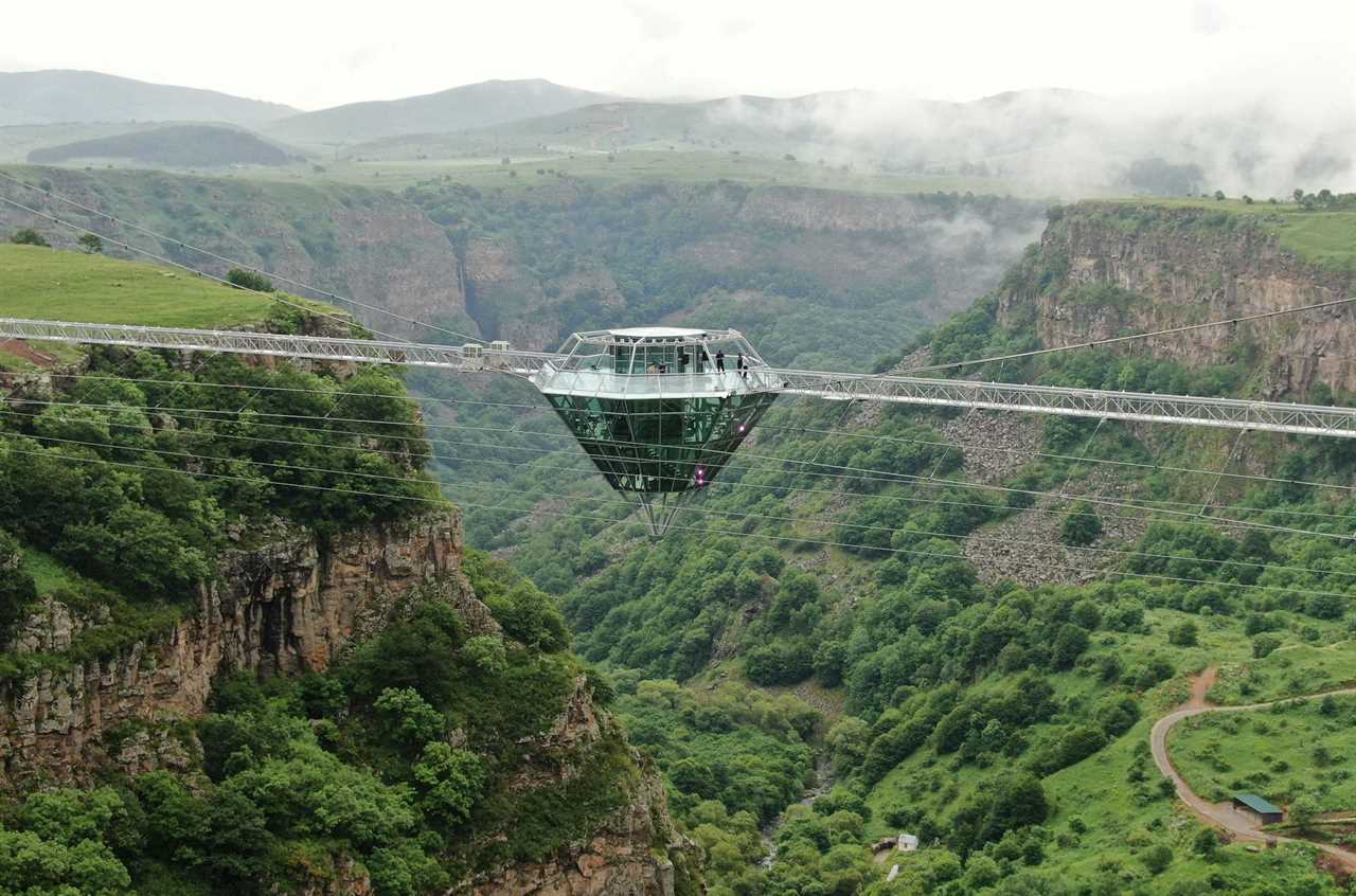 a glass bar suspended in the air in the middle of a glass bridge above Dashbashi Canyon in the country of Georgia