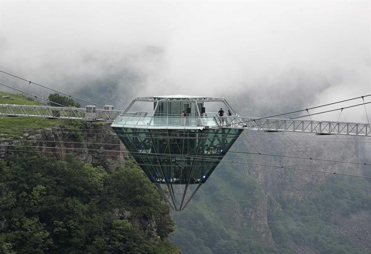 a glass bar suspended in the air in the middle of a glass bridge above Dashbashi Canyon in the country of Georgia