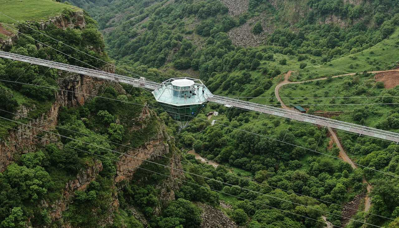 a glass bar suspended in the air in the middle of a glass bridge above Dashbashi Canyon in the country of Georgia