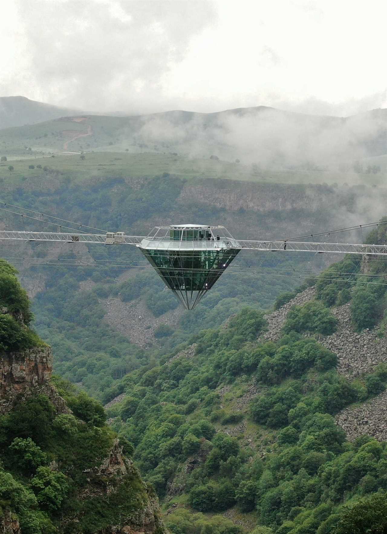a glass bar suspended in the air in the middle of a glass bridge above Dashbashi Canyon in the country of Georgia