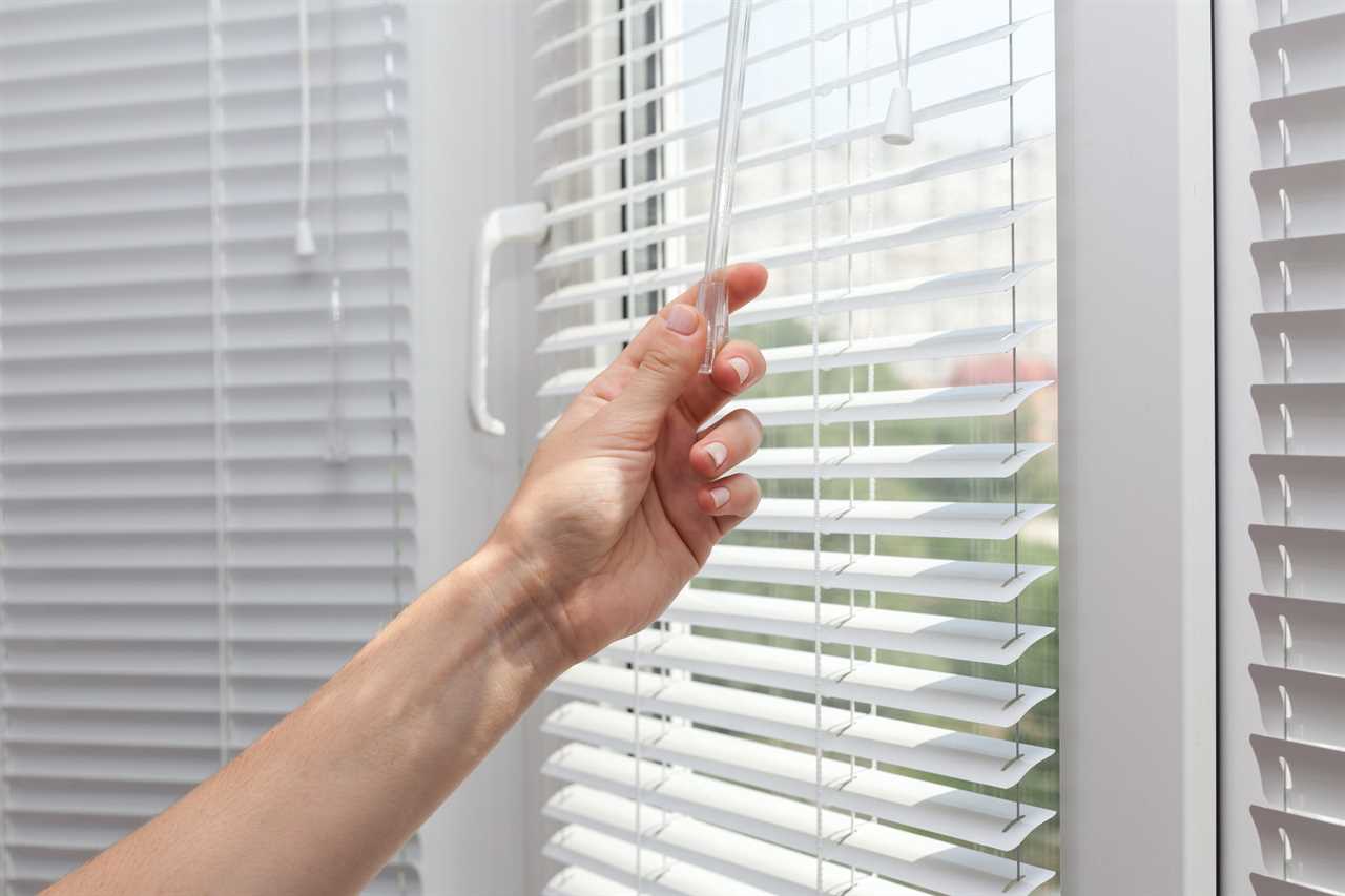 close up of hands closing the blinds on a window