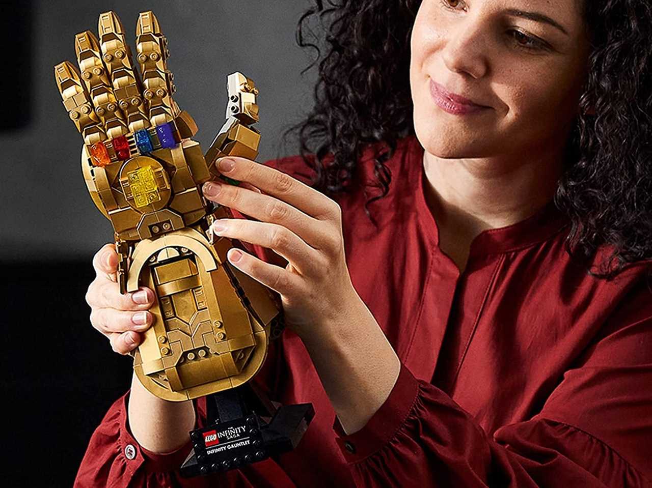 woman holding and admiring a lego infinity gauntlet