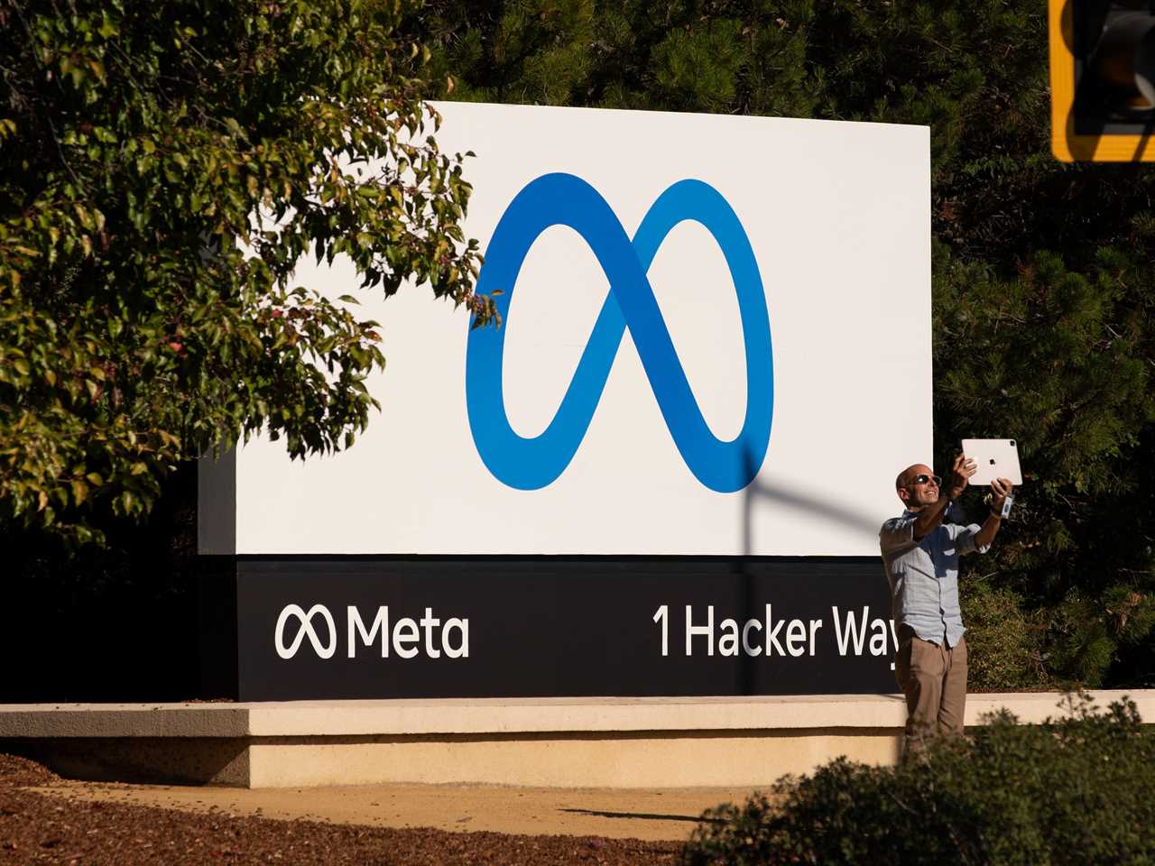 A man takes pictures in front of a sign showing logo of Meta outside Facebook headquarters on October 28, 2021 in Menlo Park, California.