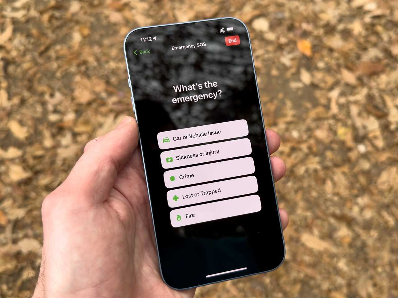 A hand showing the Apple Emergency SOS via Satellite emergency options.