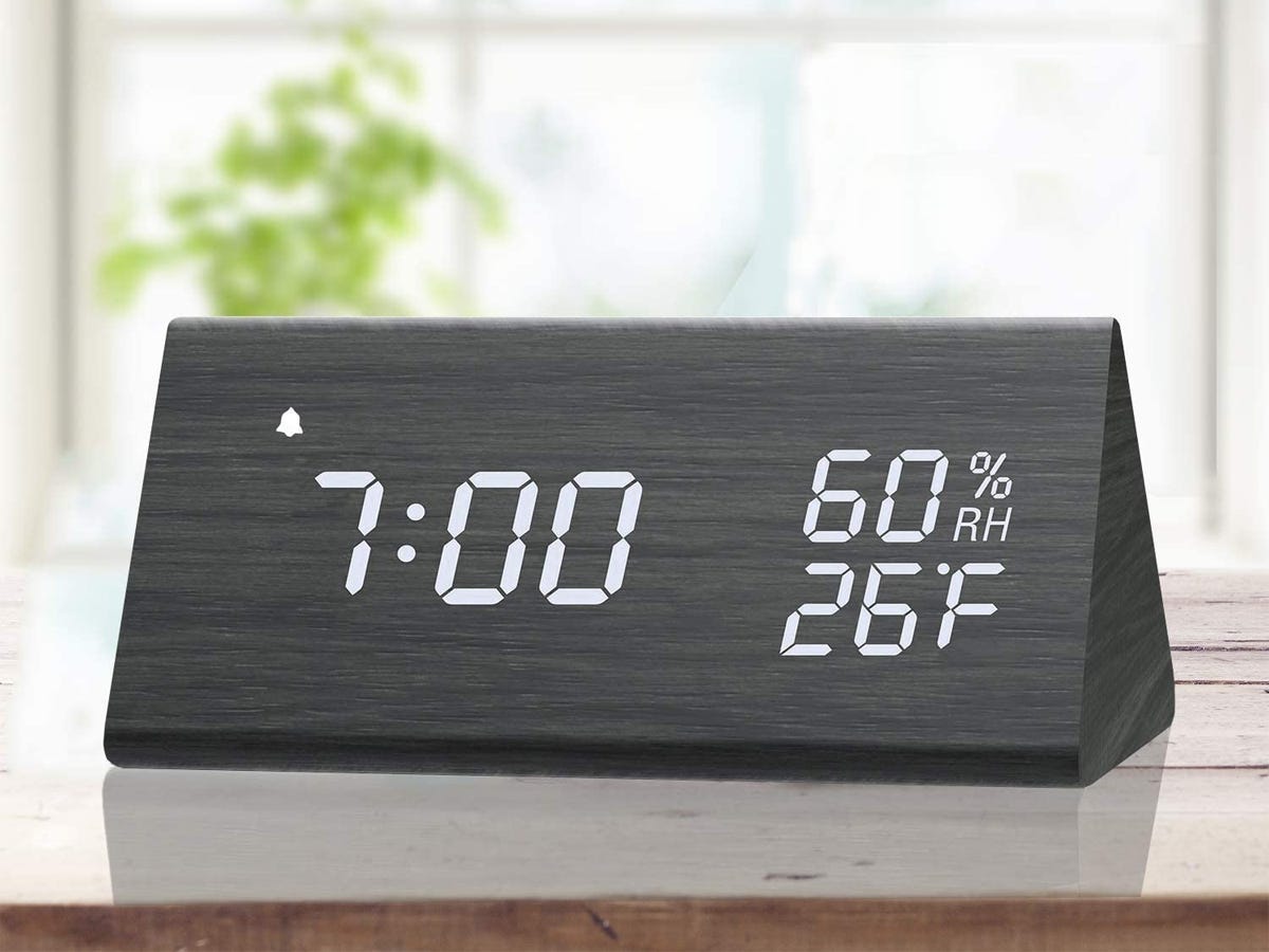 a Wooden LED Alarm Clock on a desk with a window and houseplant in the background as one of the best tech products under $50