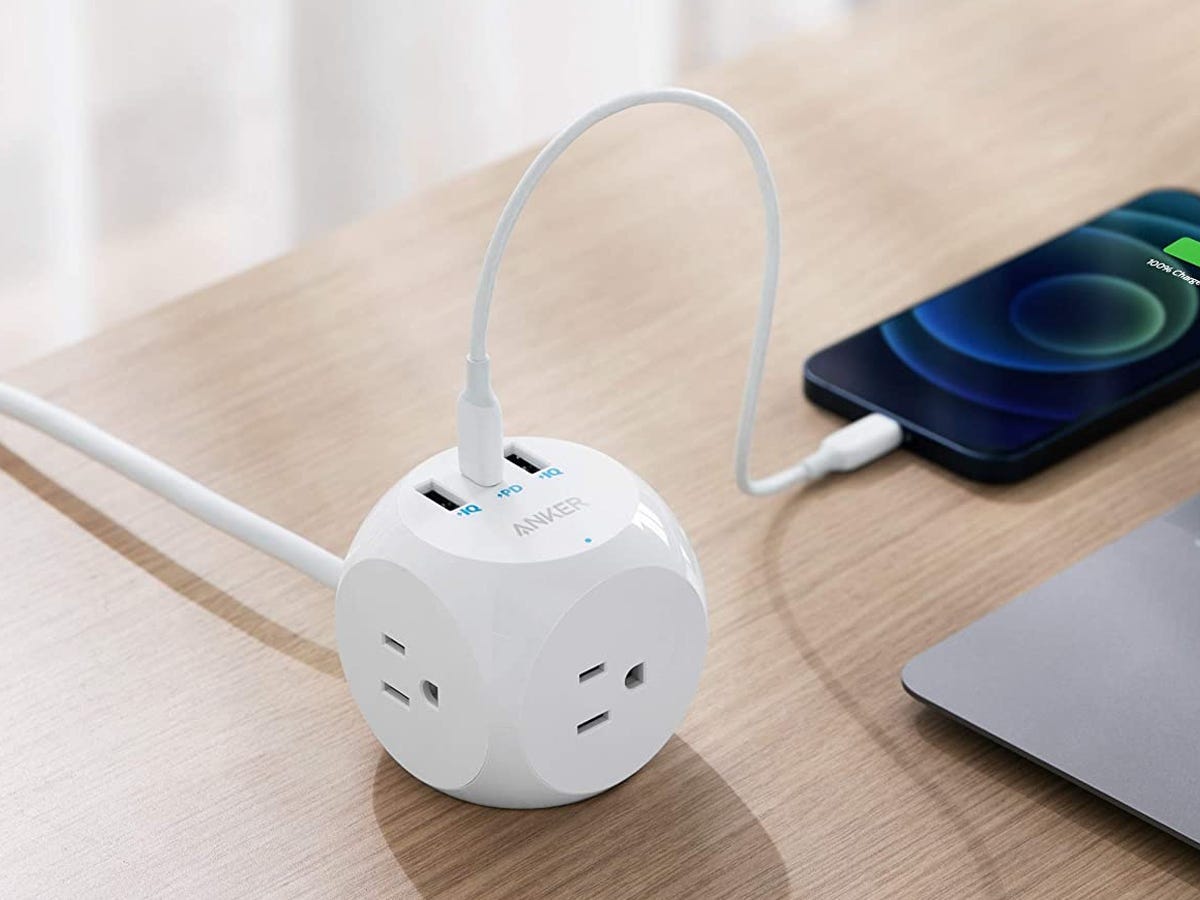 an Anker 524 Power Strip sits on a desk with a phone plugged in