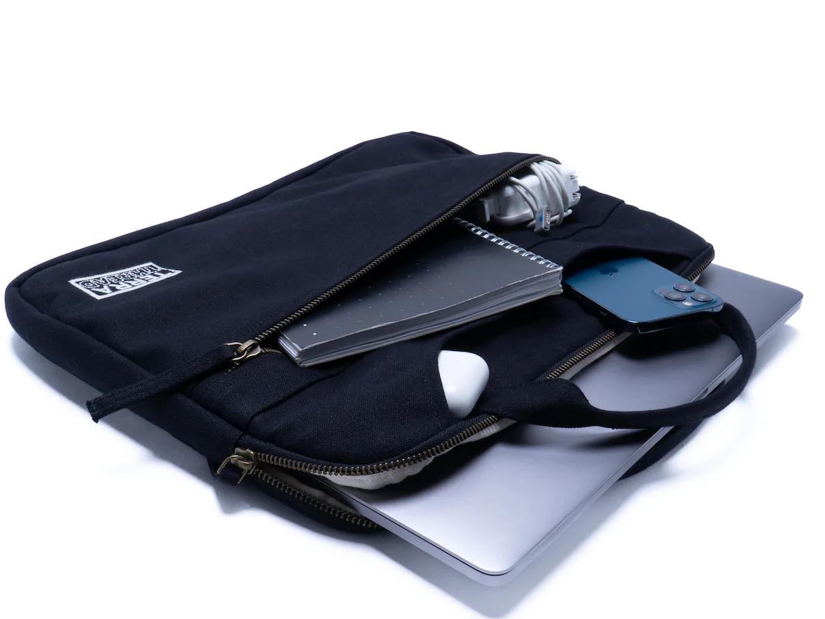 a Terra Thread Hasta Laptop Sleeve lays open with a laptop and other electronics spilling out as one of the best tech products under $50