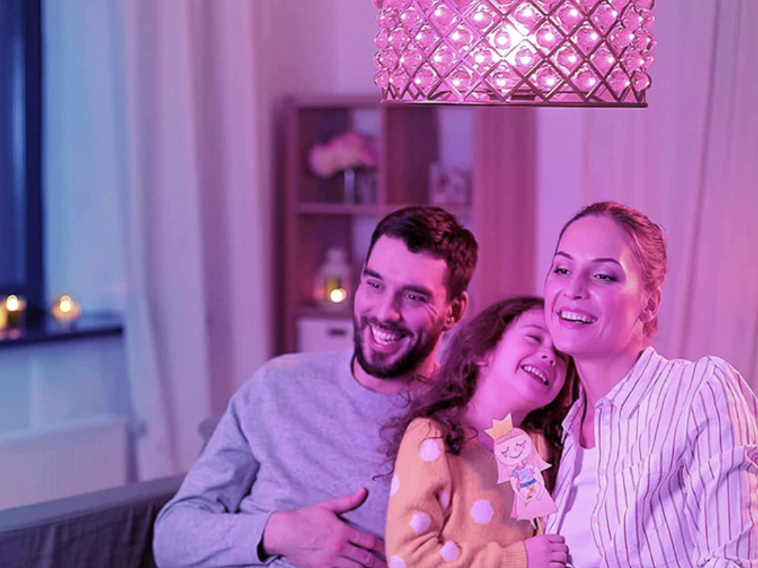 A family of three sitting in a living room under a pink lightbulb