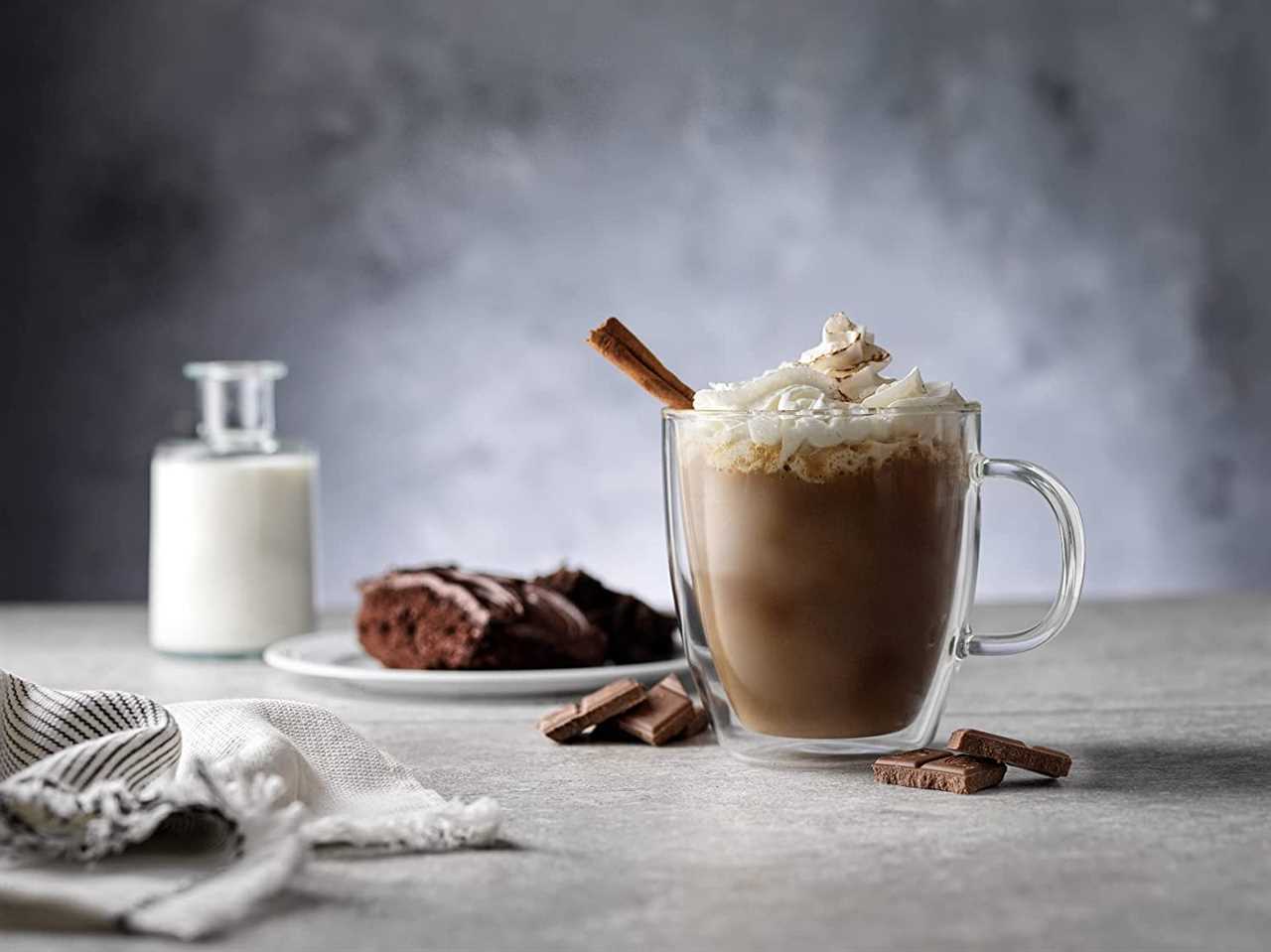 a JoyJolt Savor Double Wall Insulated Coffee Mug sits on a surface filled with hot chocolate and whipped cream, one of the clever gift ideas on sale for Black Friday