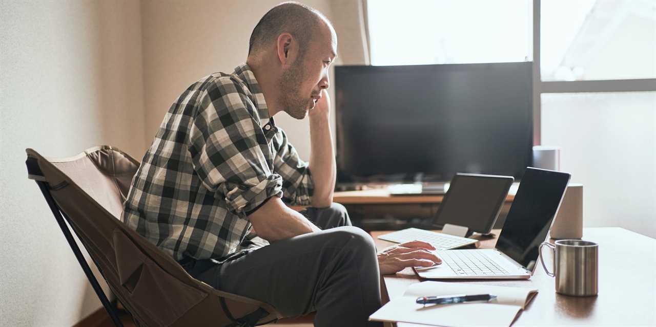 Person sitting in a chair working on their laptop and tablet.