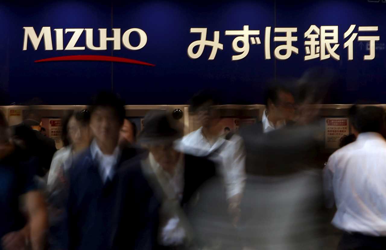 FILE PHOTO: Pedestrians walk under a logo of the Mizuho Financial Group Inc. in Tokyo, Japan, May 15, 2015. REUTERS/Yuya Shino/File Photo