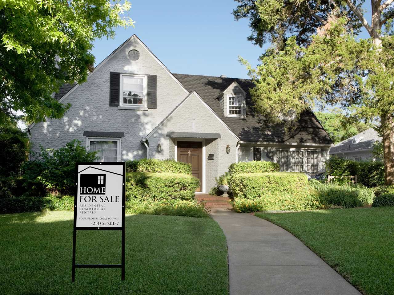 Exterior view of house with for sale sign.