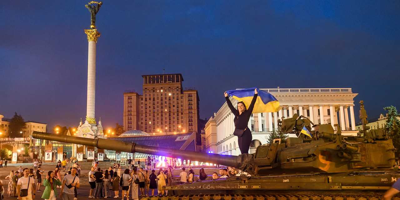 A girl with Ukrainian flag stands on a destroyed russian tank during an exhibition destroyed russian military vehicles on Khreshchatyk street in center of Kyiv, Ukraine, August 20, 2022.