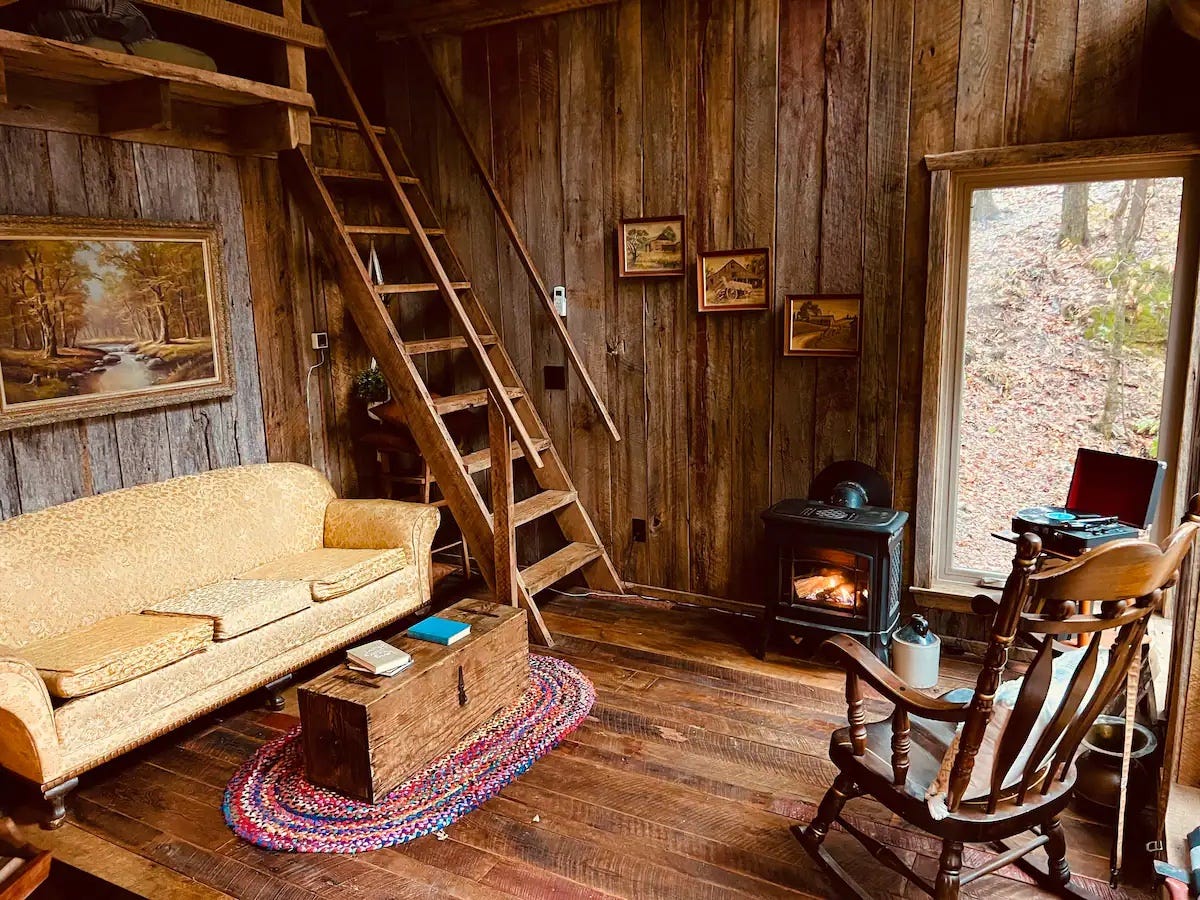 A yellow couch, coffee table, and rocking chair inside a wooden cabin