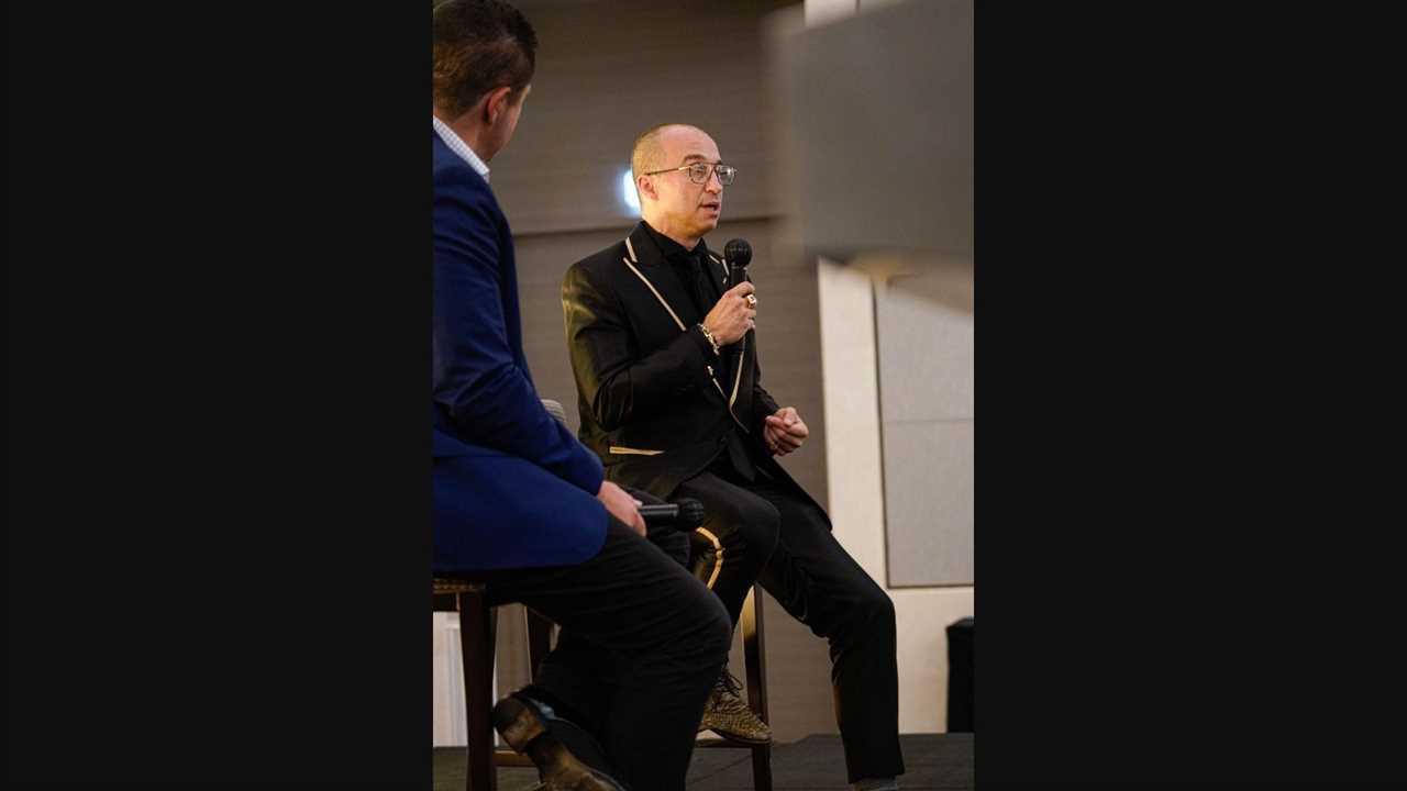 Man in black and gold suit talking on microphone